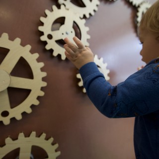 Child Exploring Interactive Gear Wall at Museum