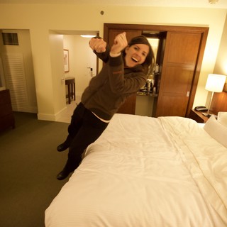 Excited Woman Leaping Onto Hotel Bed in San Francisco