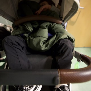Child in Stroller with Green Jacket and Patterned Shoes
