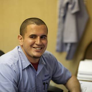 Smiling Man in Blue Shirt at Work Desk