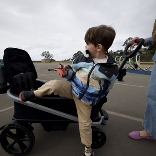 Young Boy Helping Push Stroller in Parking Lot