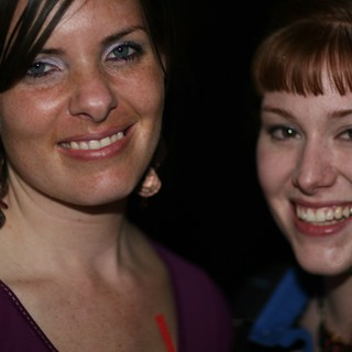 Two Smiling Women at a Nighttime Social Gathering