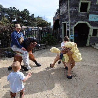 Children Enjoying Whimsical Horse Statues at Theme Park
