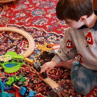 Child Playing with Wooden Train Set on Persian Rug