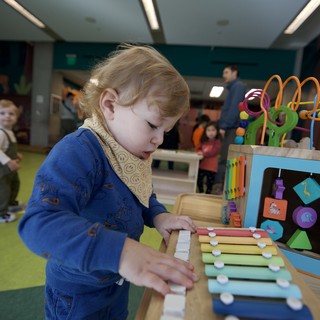 Young Child Exploring Musical Xylophone Toy at Play Center