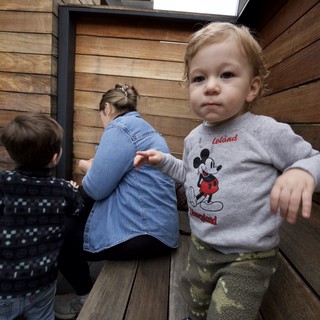 Young Child in Mickey Mouse Sweatshirt on Wooden Deck