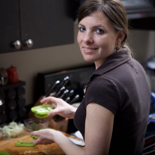Smiling Woman Chopping Green Peppers in Kitchen