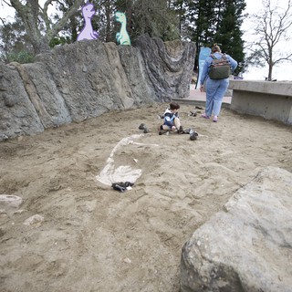 Child Playing in Dinosaur-Themed Sand Excavation Pit