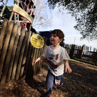 Young Boy Running Through Playground on Autumn Day