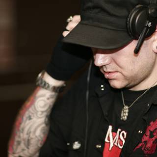 A Tattooed Man with Headphones and Baseball Cap