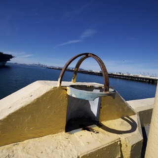 Rusted Mooring Ring on Yellow Painted Bollard at Waterfront