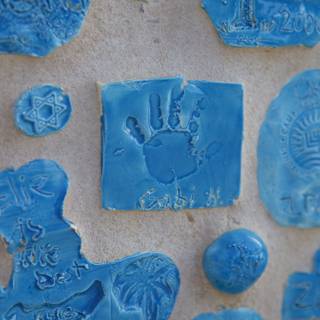 Blue handprints and symbols on ceramic tiles