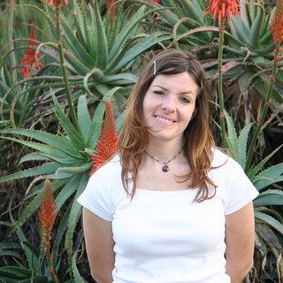 Young Woman Smiling Among Blooming Aloe Vera Plants