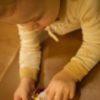 Toddler Intently Examining Colorful Book on Wooden Floor