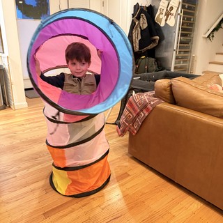 Child Playing in Colorful Pop-Up Tunnel at Home
