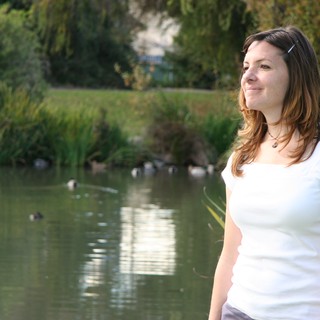 Woman Smiling Beside a Tranquil Park Pond