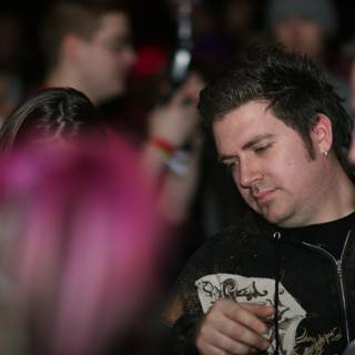 Pink-Haired Man Stands Out in Urban Nightlife Crowd