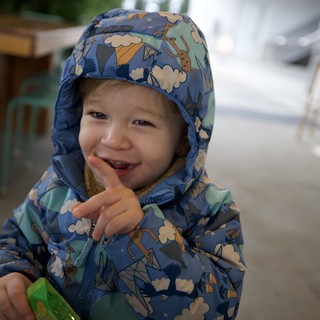 Joyful Toddler in Patterned Rain Jacket at Outdoor Cafe
