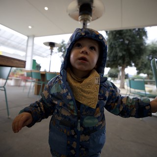 Toddler's Wonder Under Heat Lamp at Outdoor Café