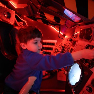 Child Exploring Spacecraft Interior at Space Center