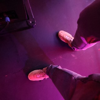 Neon Pink Sneakers on a Dark Festival Stage Floor