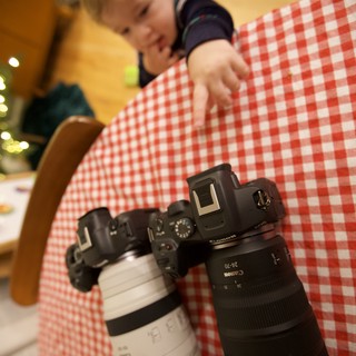 Young Photographer Reaches for Canon Camera on Checkered Table