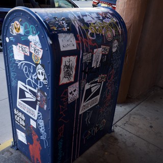 Street Art Sticker-Covered USPS Mailbox on Urban Corner