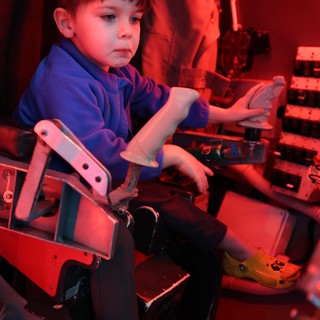 Young Boy Exploring Interactive Exhibit Under Red Lighting