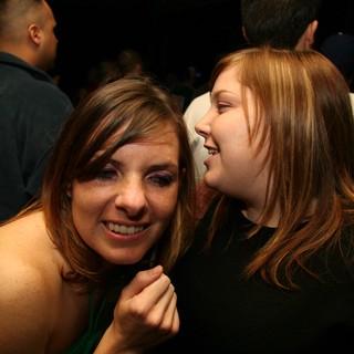 Two Friends Share a Whispered Secret at Nightclub