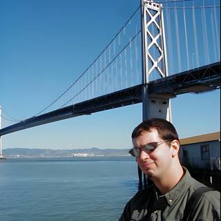 Man in Sunglasses standing in front of Suspension Bridge