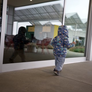 Child Explores Modern Restaurant Through Glass Door