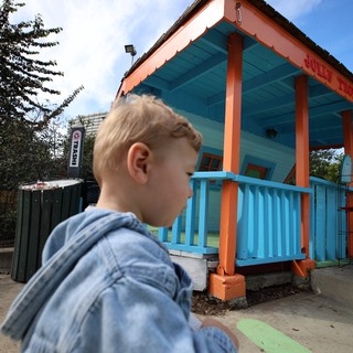 Child Gazes at Vibrant Turquoise and Orange Playhouse