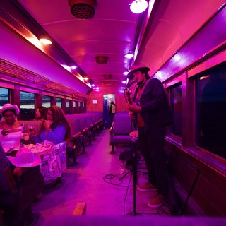Purple-Lit Vintage Train Car Performance at Twilight