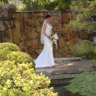 Bride Stands Gracefully Before Garden Waterfall