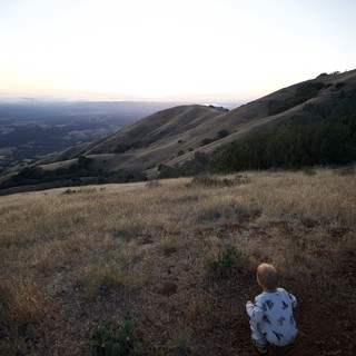 Two Children Gazing Over Golden Hills at Dusk