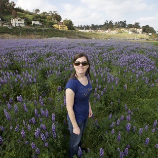 Woman Smiling Among Vast Purple Lupine Blooms
