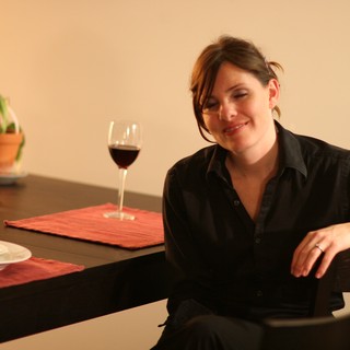Woman Smiling at Dinner Table with Red Wine