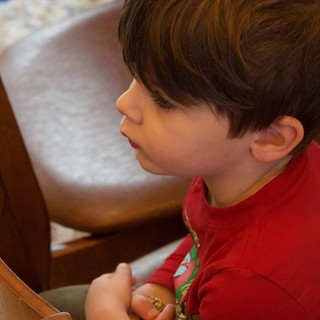 Young Boy in Red Shirt Sitting on Wooden Chair