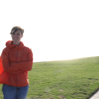 Woman in Red Jacket Smiling at Coastal Park
