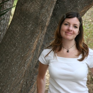 Woman Smiling Beside a Tree in Nature