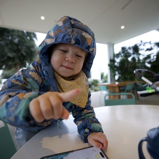 Young Child Engaging with Smartphone at Outdoor Table