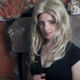 Blonde Woman Poses Against Rustic Stone Wall