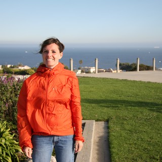 Smiling Woman in Orange Jacket by the Sea