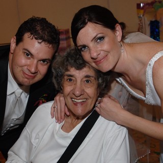 Bride and Groom Embrace Beloved Grandmother at Wedding