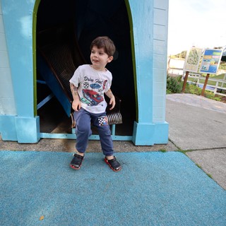 Young Boy at Colorful Playground Tunnel Entrance