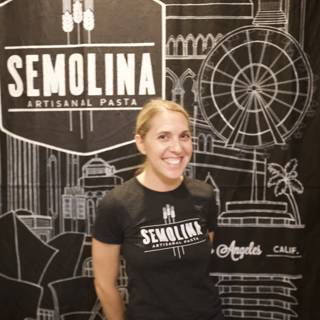 Smiling Woman Poses in Front of Semolina Sign