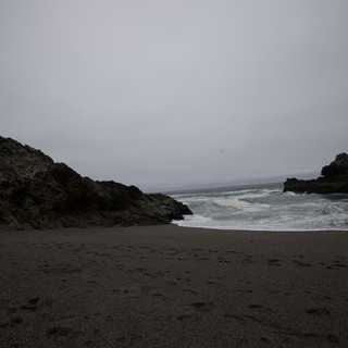 Dark Sand Cove Under Brooding Fog-Shrouded Skies