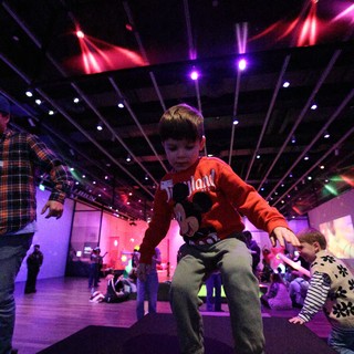 Child Dancing at Baby Rave Event Under Colorful Lights
