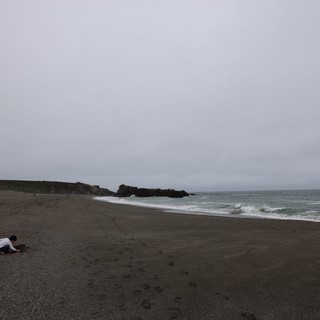 Child Playing Alone on a Moody Coastal Beach