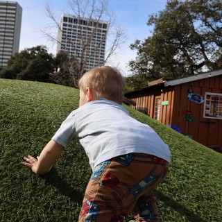 Toddler Climbing Hill in Urban Park Setting